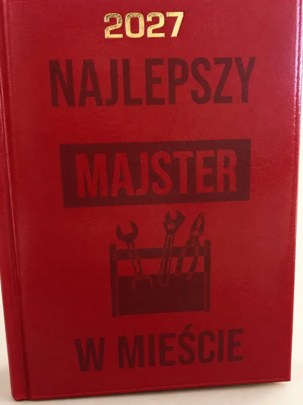 Czerwony kalendarz 2027 z napisem Najlepszy Majster w Mieście, aranżacja.