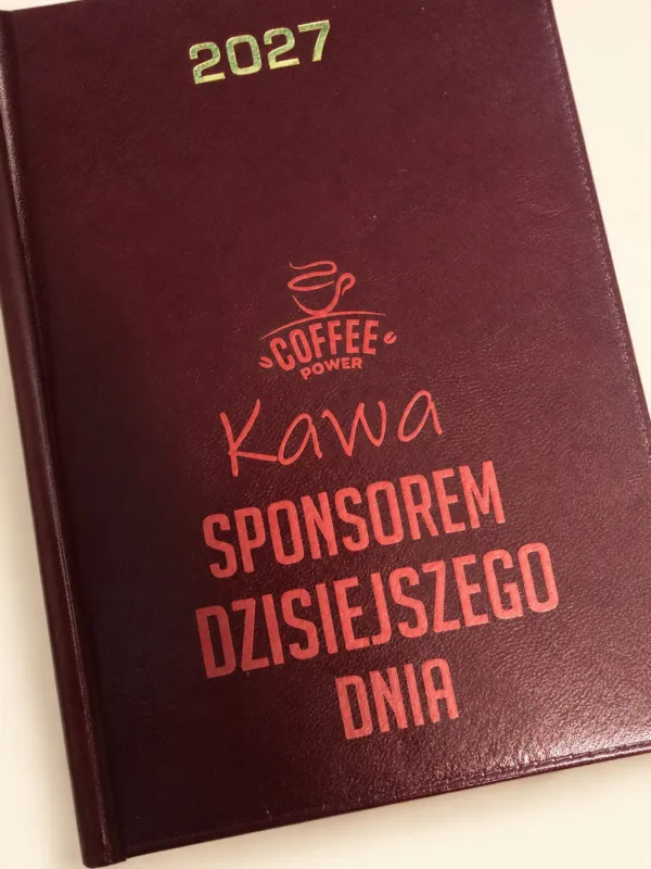 Bordowy kalendarz 2027 z napisem Kawa sponsorem dzisiejszego dnia, aranżacja.