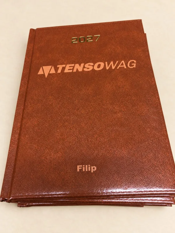 Brązowy kalendarz 2027 z logo TENSOWAG i imieniem Filip, aranżacja.