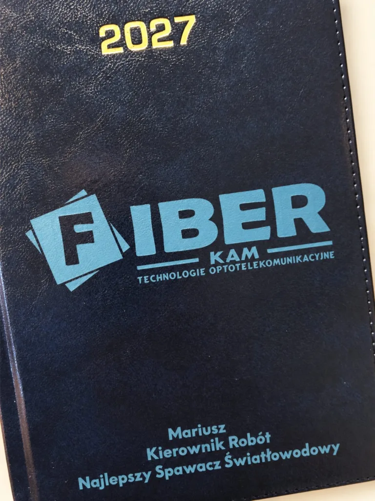 Granatowy kalendarz 2027 z logo FIBER KAM, imieniem i stanowiskiem, aranżacja.