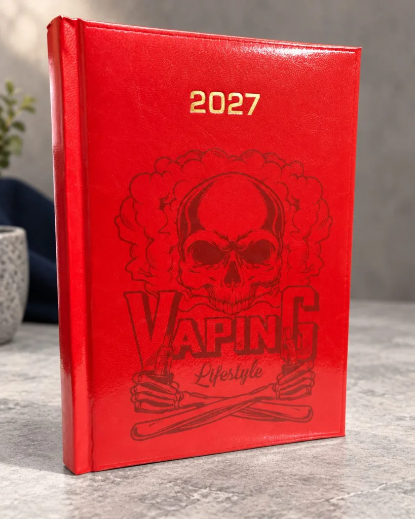 Czerwony kalendarz 2027 z grafiką czaszki w chmurze dymu i napisem Vaping Lifestyle na szarym blacie, aranżacja.